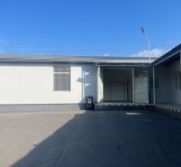 Skladové a výrobné priestori s kanceláriami 130 m² /180 m² /198 m² BB - V areáli skladov a hál v okrese Banská Bystrica, pred bielou budovou s dverami.