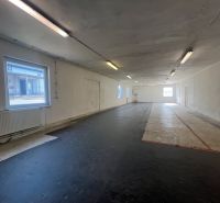 Skladové a výrobné priestori s kanceláriami 130 m² /180 m² /198 m² BB - Interiérová fotografia znázorňuje prázdny priestor s čiernou podlahou a oknami, Sklady a haly.