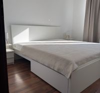 Prenájom 3-izb. byt Ku Bratke - zariadený - Spálňa v 3-izbovom byte s posteľou, závesmi a podlahou s dreveným dekorom.