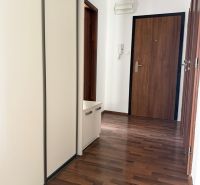 Prenájom 3-izb. byt Ku Bratke - zariadený - Vstupná chodba v 3-izbovom byte s podlahou s dreveným dekorom a bielymi skriňami.