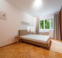 2 izbový kompletne zariadený byt Sever na prenájom - Spálňa v 2-izbovom byte s veľkou posteľou, podlahou s dreveným dekorom a šatníkom.