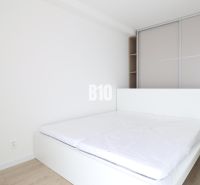 2 izbový byt na predaj Považská Bystrica - Svetlá spálňa v 2-izbovom byte s posteľou a vstavanou skriňou, podlaha s dreveným dekorom.