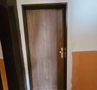 Predáme novorekonštruovanú garzonku v Šali - Vstupné dvere s dreveným dekorom a čiernou rohožou, Garsónka.