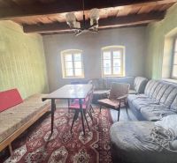 Na predaj vidiecky rodinný dom - Žarnovica/Brehy D045ZL - Obývacia izba v rodinnom dome s dreveným stropom, sedačkou a vzorovaným kobercom.
