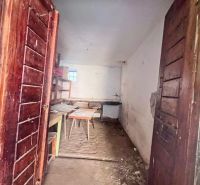 Na predaj vidiecky rodinný dom - Žarnovica/Brehy D045ZL - Drevené dvere vedú do miestnosti rodinného domu s nábytkom a surovou podlahou.