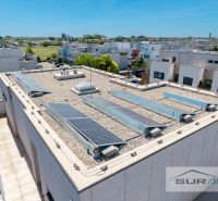 Nový 3-izbový byt 82 m² | Terasa 97 m² | Mesačná ulica | Hviezdoslavov - Budova so solárnymi panelmi na Mesačnej ulici v Hviezdoslavove obklopená zástavbou.