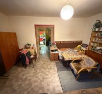 Rodinný dom s veľkým pozemkom v meste Nesvady  - Obývacia izba v rodinnom dome so starožitným nábytkom a kreslami, podlaha s dreveným dekorom.