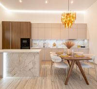 MODERNÝ 4-IZBOVÝ BUNGALOV | ZEMPLÍNSKA ŠIROKÁ - Kuchyňa s ostrovčekom, podlaha s dreveným dekorom, jedálenský stôl a zlatý luster.