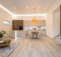 MODERNÝ 4-IZBOVÝ BUNGALOV | ZEMPLÍNSKA ŠIROKÁ - Kuchyňa a obývačka v rodinnom dome s dekoratívnym svietidlom a podlahou s dreveným dekorom.