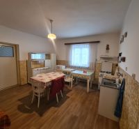 Na predaj rodinný dom Dulovce ! - Kuchyňa v rodinnom dome s podlahou s dreveným dekorom, jednoduchý nábytok a jedálenský stôl.