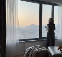 SKY PARK 3izbový byt a výhľad na hrad - Žena pozorujúca výhľad z 3-izbového bytu s kvetmi a podlahou s dreveným dekorom.