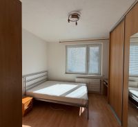 3 izbový byt s balkónom v meste Levice - Spálňa v 3-izbovom byte s posteľou a vstavanou skriňou, podlaha s dreveným dekorom.