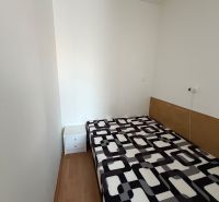 3 izbový byt s balkónom v meste Levice - Jednoduchá izba v 3-izbovom byte s posteľou a podlahou s dreveným dekorom.