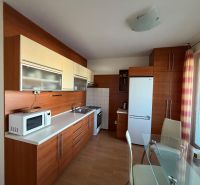 3 izbový byt s balkónom v meste Levice - Kuchyňa v 3-izbovom byte s bielou linkou a podlahou s dreveným dekorom.