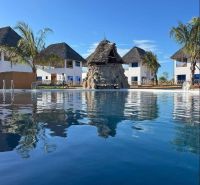 Dom pri pláži s vlastnou studňou a bazénom - Zanzibar, Uroa O578ZL - Rodinný dom v Zanzibare obklopený palmami pri bazéne pod modrou oblohou.