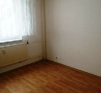 3 izbový byt na sidlisku Stráňany - Miestnosť v 3-izbovom byte s podlahou s dreveným dekorom, závesom a radiátorom.