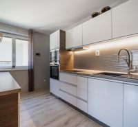 Predaj RD s pozemkom 1008 m2, Trenčín - Istebník - Kuchyňa v rodinnom dome s bielymi skrinkami, podlahou s dreveným dekorom a oknom.