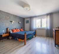 Predaj RD s pozemkom 1008 m2, Trenčín - Istebník - Spálňa v rodinnom dome s podlahou s dreveným dekorom, tapetou a masívnym nábytkom.