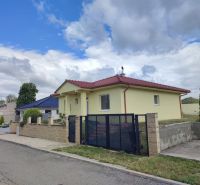 Na predaj zariadený 3izbový bungalov v obci Radimov - Rodinný dom v Radimove s červenou strechou, udržiavanou záhradou a betónovým plotom.