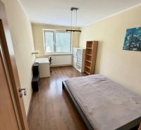Prenájom pekný 4 izbový byt, Wolkrova ulica, Bratislava V. Petržalka - Spálňa v 4-izbovom byte s posteľou, stolom a podlahou s dreveným dekorom.