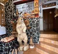 Na predaj penzion  – Štôla, Vysoké Tatry O560ZL - Interiér vily s drevenými sochami zvierat a kamennými stenami.