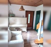 Exkluzívne na predaj, čarovný rodinný dom / chalupa v lone prírody - Interiér rodinného domu s bielym klavírom, podlaha s dreveným dekorom, schody a drevený strop.