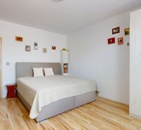 Moderný 3-izbový byt s balkónom a 2 parkovacími miestami - Ludanice - Svetlá spálňa v 3-izbovom byte s posteľou a podlahou s dreveným dekorom.