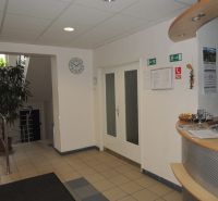 Prenájom kancelárie Ružinov, Sabinovská ul., 33m2,43 m2  - Recepcia v kanceláriách s pultom, bielymi stenami a vchodovými dverami.