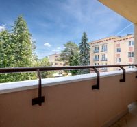 TOP LOKALITA - 3i 67m2 + loggia - Švermova Trenčín - Pohľad z balkóna 3-izbového bytu na Švermovej ulici v Trenčíne s výhľadom na zeleň a budovy.