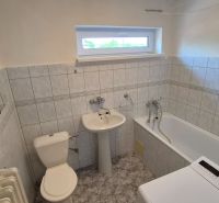 Tehlový 2-izbový byt s vlastným kúrením vo Vrbovom - Kúpeľňa v 2-izbovom byte s vaňou, umývadlom, práčkou a kachličkovanými stenami.