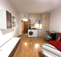 ☎️ 0918/197 701 Na prenájom garsónka s balkónom aj s výťahom   v centr - Rekreačný apartmán so vstavanou kuchyňou, červenou sedačkou a podlahou s dreveným dekorom.