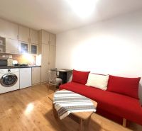 ☎️ 0918/197 701 Na prenájom garsónka s balkónom aj s výťahom   v centr - Rekreačný apartmán s červenou sedačkou, kuchynským kútom a podlahou s dreveným dekorom.