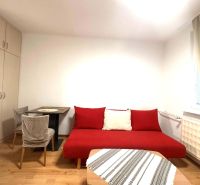 ☎️ 0918/197 701 Na prenájom garsónka s balkónom aj s výťahom   v centr - Izba v rekreačnom apartmáne s červenou pohovkou, stolom, a podlahou s dreveným dekorom.