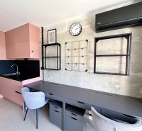 Plne vybavená garzónka s 24/7 strážnou službou a klímou – Kysucká - Garsónka s podlahou s dreveným dekorom, ružovou kuchyňou a sivými pracovnými stoličkami.