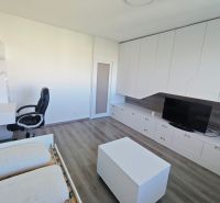 Na prenájom 1 izbový byt, 34 m2, Bratislava, Petržalka, Lachova ulica - Interiér 1-izbového bytu s pracovným stolom, televízorom a podlahou s dreveným dekorom.