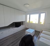 Na prenájom 1 izbový byt, 34 m2, Bratislava, Petržalka, Lachova ulica - Interiér 1-izbového bytu s bielymi skrinkami, podlahou s dreveným dekorom a veľkými oknami.