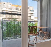 I Slnečnice – Zóna mesto moderný 1-izb byt s loggiou - Výhľad z 1-izbového bytu na balkón so stolom a stoličkami.