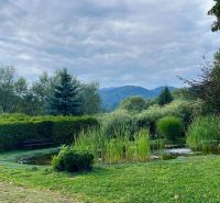Predaj- Rodinný dom -Stankovany - Záhrada s rybníkom a lavičkou pri rodinnom dome v Stankovanoch, obklopená zeleňou a horami.