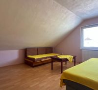 Rodinný dom pre veľkú rodinu s priestorom a súkromím – Polomka - Svetlá podkrovná izba s dvomi posteľami, stolíkom a podlahou s dreveným dekorom.
