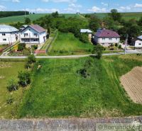 Slnečný stavebný pozemok 1 186 m² - Karná | možnosť dokúpiť 1 ha - Pozemky - bývanie v Karnej: zelené plochy, domy a príjazdová cesta pod modrou oblohou.