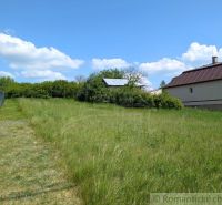 Slnečný stavebný pozemok 1 186 m² - Karná | možnosť dokúpiť 1 ha - Trávnaté pozemky na bývanie v Karnej s výhľadom na dom a modrú oblohu.