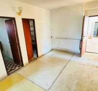 Na predaj 6-izbový rodinný dom (dvojdom) v Pažiti, pozemok 1445 m² - Interiér so starou podlahou, drevenými dverami a radiátorom v rodinnom dome.