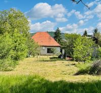 Na predaj 6-izbový rodinný dom (dvojdom) v Pažiti, pozemok 1445 m² - Rodinný dom v Pažiti obklopený stromami a trávnikom s červenou strechou.