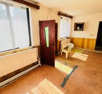 Na predaj 6-izbový rodinný dom (dvojdom) v Pažiti, pozemok 1445 m² - Interiér rodinného domu s otvorenými dverami, plastovými stoličkami a veľkými oknami.