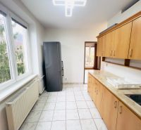 Na predaj 2-izbový byt Trenčianske Teplice - Kuchyňa v 2-izbovom byte s oknami, dlažbou a dreveným dekorom skríň.