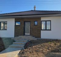 Bungalov v centre obce Cabaj Čápor, Wágnerova ulica, Dom č.1 - Rodinný dom v Cabaji-Čápore s bielou fasádou a kamenným obložením, svahovitý terén.