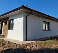 Bungalov v centre obce Cabaj Čápor, Wágnerova ulica, Dom č.1 - Rodinný dom v Cabaj-Čápore s bielou fasádou a kamennými obkladmi na vstupnej stene.