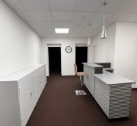 Prenájom Kancelárie 110 m² v centre Ružomberka - Kancelárie s recepciou, bielymi skrinkami a hnedým kobercom, podlaha s dreveným dekorom.