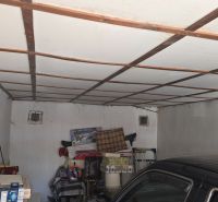 NA PREDAJ MUROVANÁ GARÁŽ 18 m² VO ZVOLENE – ELEKTRINA, VLASTNÝ POZEMOK - Garáže s bielym ventilátorom, uskladnenými vecami a zaparkovaným autom.