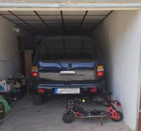 NA PREDAJ MUROVANÁ GARÁŽ 18 m² VO ZVOLENE – ELEKTRINA, VLASTNÝ POZEMOK - Garáž s autom a elektrickou kolobežkou, uloženými predmetmi a kresbou na dverách.